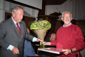 Jan Roosloot ontvangt de oorkonde die behoort bij zijn lidmaatschap van verdienste, en een mooi boeket, uit handen van Niek Weel